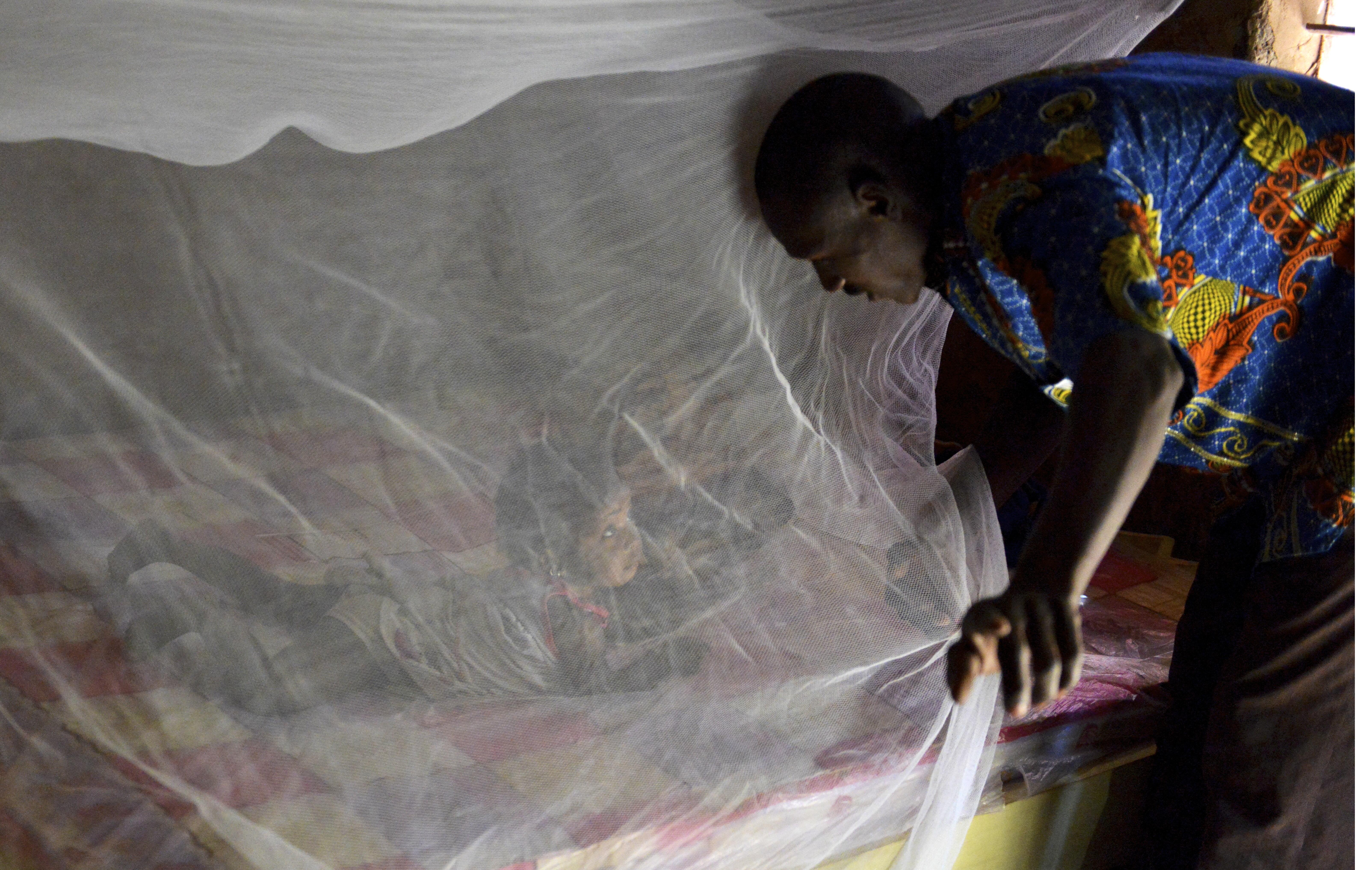 Father putting his daughter under a bednet in Burkina Faso Father putting his daughter under a bednet in Burkina Faso
