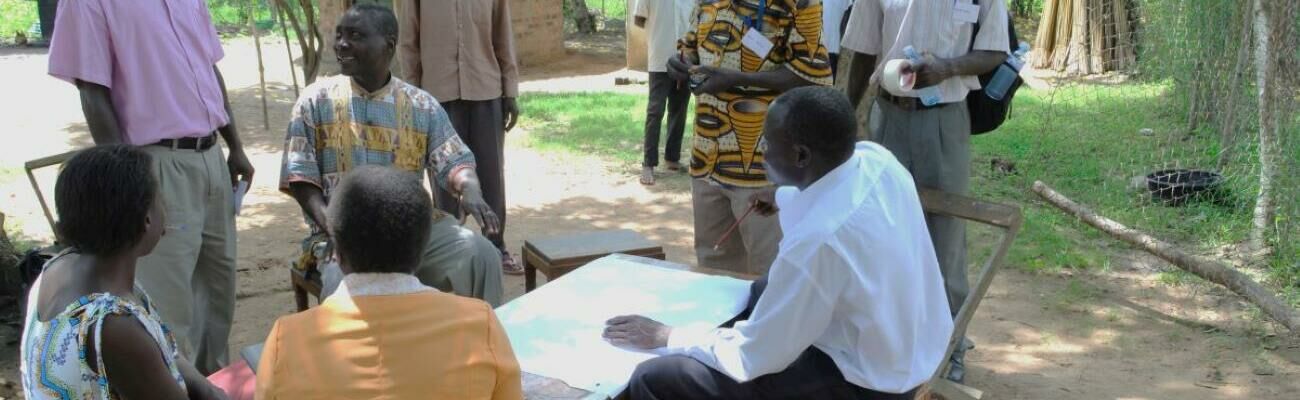 A group of people sitting round a table looking at a map.